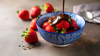 A Decadent Delight: Sweet Strawberry Covered in Silky Melted Chocolate Drizzle Nestled in a Charming Blue Patterned Bowl