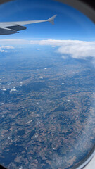 Fototapeta premium aerial view from plane window in flight with part of wing and earth below