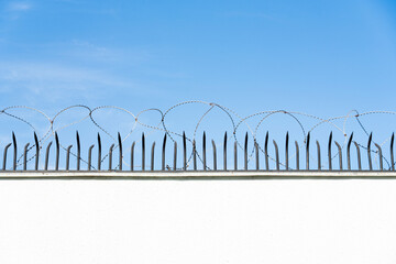 Barbed wire and security fence against blue sky