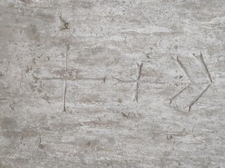 An arrow symbol is carved into a rough stone surface. The markings appear weathered, suggesting age and history.