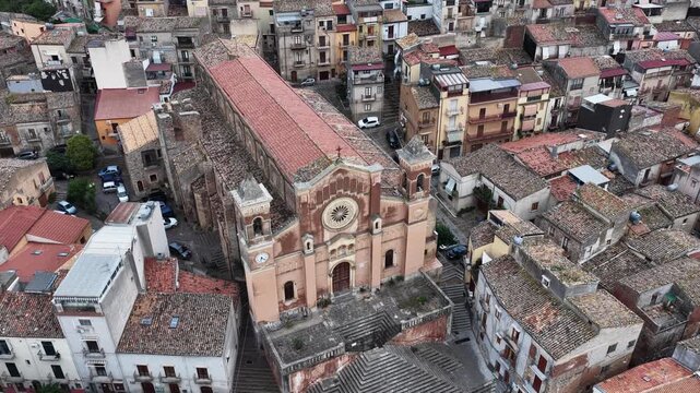 Aerial drone view of Collesano Sicilian mountain town at sunset with Basilica San Pietro church and historic stone streets in the Madonie Mountains, Sicily, Italy. Old mountain town in Sicily