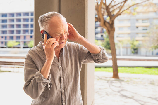 Senior man talking on smartphone outdoors in city - Powered by Adobe