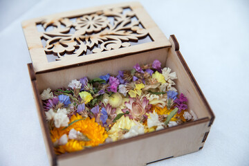 Decorative wooden box filled with assorted dried flowers in bright colors. Natural rustic arrangement ideal for eco design, aromatherapy, or wedding decoration concepts.