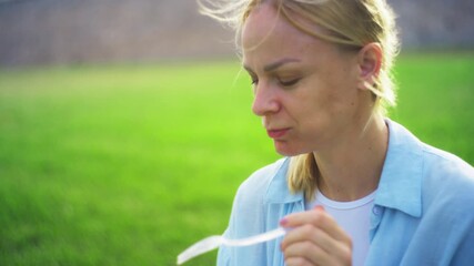 Blonde woman smiling while enjoying fresh vegetarian salad with cherry tomatoes and crisp lettuce during relaxed picnic in sunlit green meadow, savoring healthy flavors - Powered by Adobe