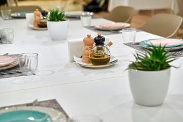 Elegant Dining Table Setup with Olive Oil, Pepper, and Salt Shakers Amidst Decorative Plants for a Cozy Gathering Atmosphere
