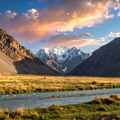 Mountain valley at golden hour, river flowing through a high-altitude meadow. Snow-capped peaks rise in the background