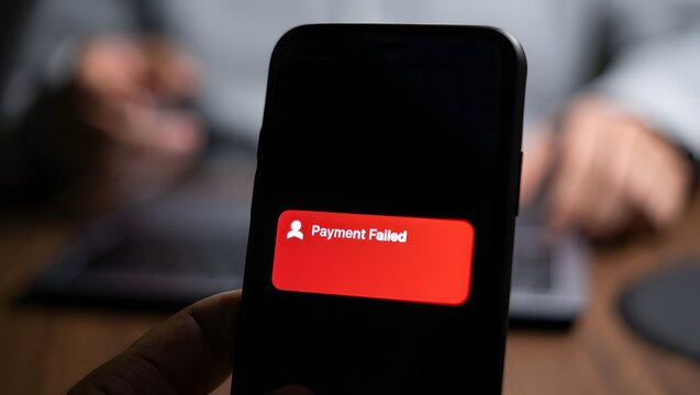Person holding a smartphone displaying the adobe creative cloud logo on a red background