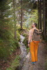 Male Backpacker hikinga  Waalweg beside a forest irrigation channel between Stanz and Grins in Tyrol, autumn greens and tranquil mood; ideal for hiking and eco‑tourism ads.