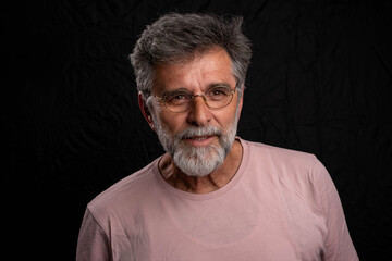 Bearded mature businessman in serious low key portrait isolated on dark studio background with...