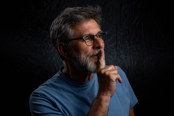 Bearded mature businessman in serious low key portrait isolated on dark studio background with chiaroscuro effect	