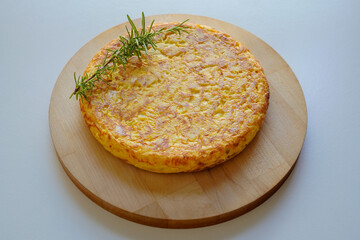 Homemade Spanish omelette (tortilla de patatas)  placed on a wooden plate