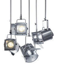 Overhead array of metallic spotlights, varying angles, emitting bright light against black