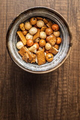 Salted snack. Coated peanuts and mini crackers in bowl on wooden table.