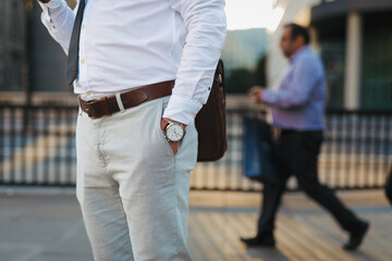 Businessman wearing wristwatch and formal clothes in city.