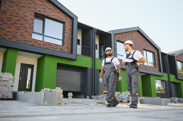 Two builders on the background of new cottages. The work is done