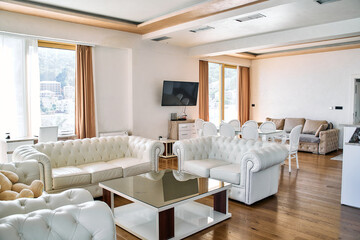 Elegant and Modern Living Room Featuring Stylish White Leather Sofas, Contemporary Furniture, and Abundant Natural Light Creating an Inviting Atmosphere