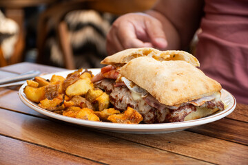 Typical chivito sandwich from Uruguay served with rustic potatoes