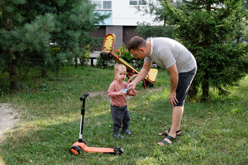 Father and son enjoy a playful moment together in a  park while preparing for a fun scooter ride
