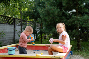 Children playing in the sandbox. Brother and sister spending time together