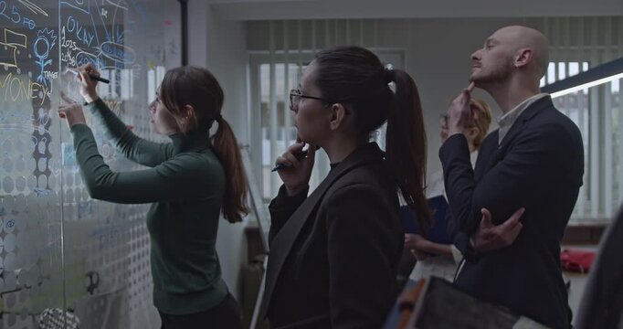 Business team analyzes data on a transparent whiteboard during a strategic planning meeting to enhance and optimize their work. - Powered by Adobe