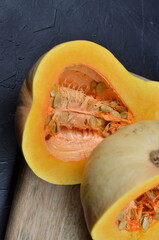 Freshly cut squash reveals vibrant orange flesh and seeds, showcasing the natural textures and colors of this nutritious vegetable on a wooden cutting board