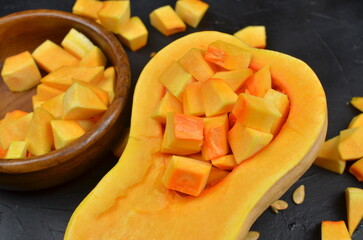 Fresh butternut squash cut into cubes, displayed in a wooden bowl, showcasing vibrant orange and yellow colors, emphasizing healthy cooking and nutritious ingredients