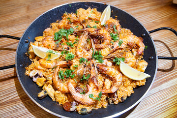 Typical Spanish dish - seafood paella with mussels, king prawns and squids in frying pan on wooden table ready for dinner