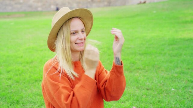 Joyful and lovely woman donning felt hat, grinning as takes pleasure in serene day outside at lush park, reveling in happiness and freedom that nature brings during tranquil interlude