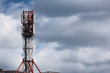 A Red And White Steel Lattice Telecommunication Tower With Antennas Against A Dramatic Dark Cloudy Sky. Mobile Communication And 5G Network.