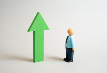 An office worker looks at a green growth arrow. Assess growth and success. Be a role model. Business success. Motivation, professional achievement, and goal setting. Personal development