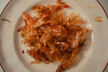 Peels of fried shrimps and langoustines on a plate. Skins after eating shrimps.