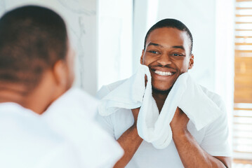 Obraz premium Male Beauty Care. Smiling African American Man Wiping Face With Towel In Bathroom, Handsome Young Black Guy Standing Near Mirror, Making Morning Self-Care Routine, Selective Focus On Reflection
