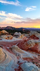Colorful, sculpted rock formations at sunset.  A high-angle view of layered,  whimsical rock formations.  Soft, pastel hues of pink, orange, and white.  Dramatic sky with clouds