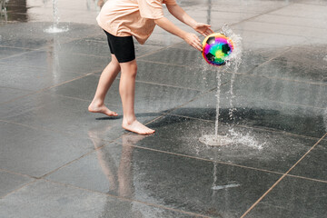 Child enjoying water games with colorful ball outdoors