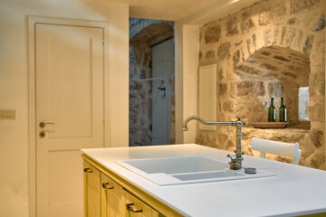 A Modern Kitchen Interior Featuring Minimalist Design Elements with Natural Stone Walls and Sleek Fixtures for a Cozy Cooking Space