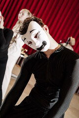 A pantomime actor in a white mask and black suit. Close-up.