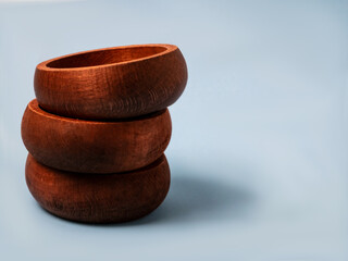 Stack of three round wooden bowls on light blue background