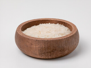 White rice grains in a round wooden bowl on a white background