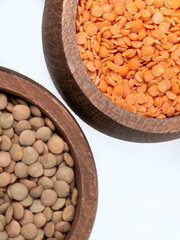 Red and green lentils in wooden bowls on white background top view
