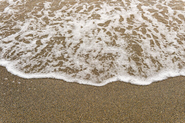 Close-up texture of wave and wet beach.