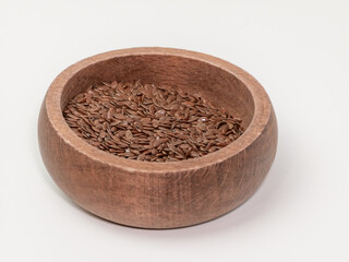 Brown flax seeds in a wooden bowl on white background
