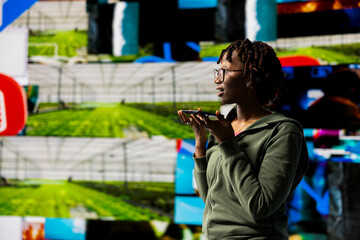 Fototapeta premium Mesmerized woman holding smartphone celebrating freedom of unlimited video content in metaverse. Person using mobile phone to look at online video channels, isolated over giant digital wall backdrop