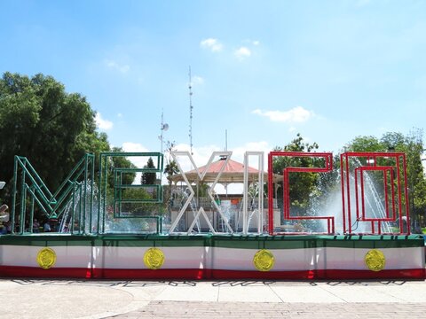 Mexico letter sign in traditional Mexican flag colors in a colonial town plaza - Powered by Adobe