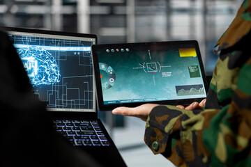 Close up of military server room engineers analyzing neural networks powered surveillance data together. Data center army specialists comparing AI generated target coordinates