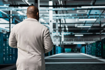 Technician walking in server room, overseeing mainframes gear used for managing databases. IT expert in data center workplace doing checkup on rackmounts storing information