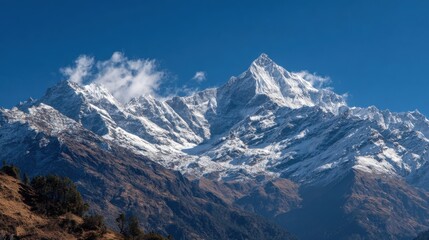 Fototapeta premium Majestic snow-covered mountains rise prominently against a bright blue sky.