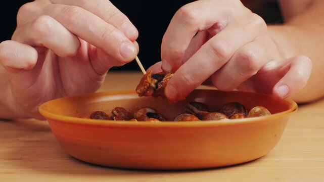 French snails, Close up of traditional spanish tapas - the boiled snails in tomato sauce with garlic and chili in black iron pan