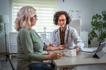 Female doctor checking blood pressure of senior woman in the doctors office