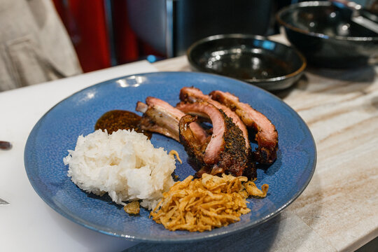 Pork ribs with sticky rice on a round plate inside a restaurant