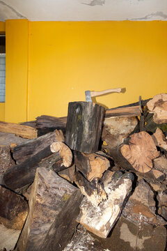 Hand axe embedded in a log atop a stack of firewood